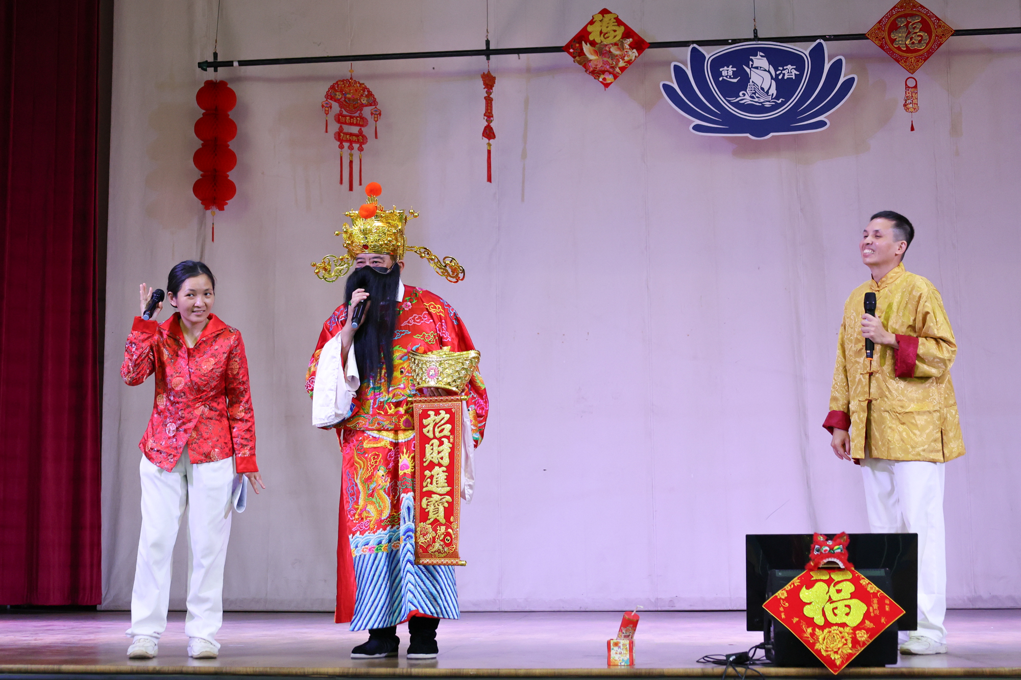 志工林志安化身财神爷，手持金元宝，亲切地与大家打招呼。