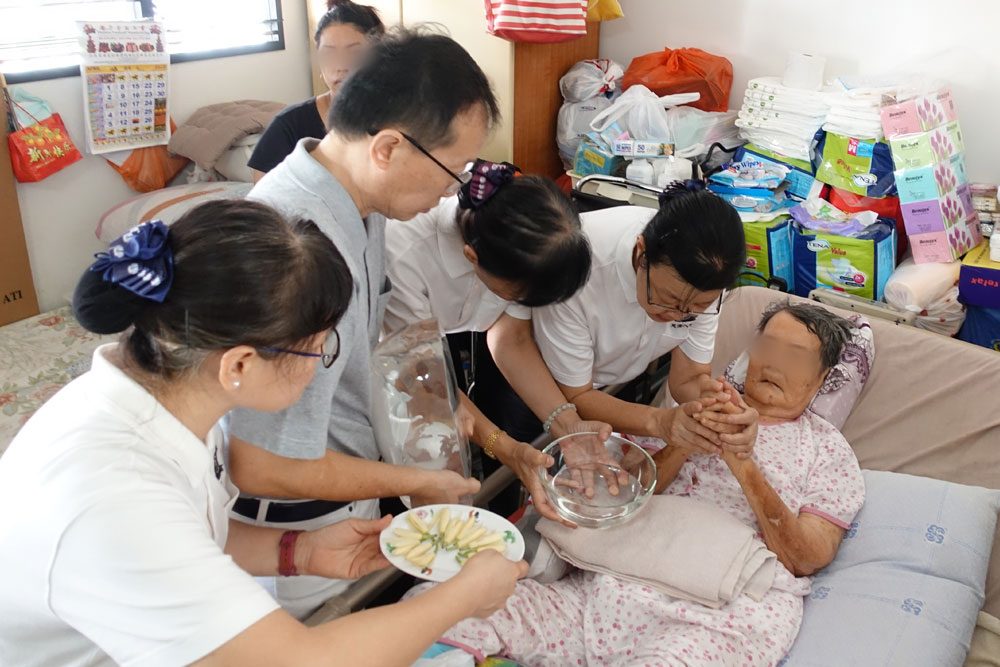 志工与医护人员把琉璃佛送到陈阿嫲面前，为她献上爱与祝福。